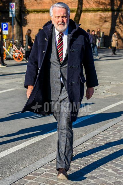 Men's coordinate and outfit with plain navy duffle coat, plain white shirt, brown plain toe leather shoes, gray checked suit, and multi-colored regimental tie.