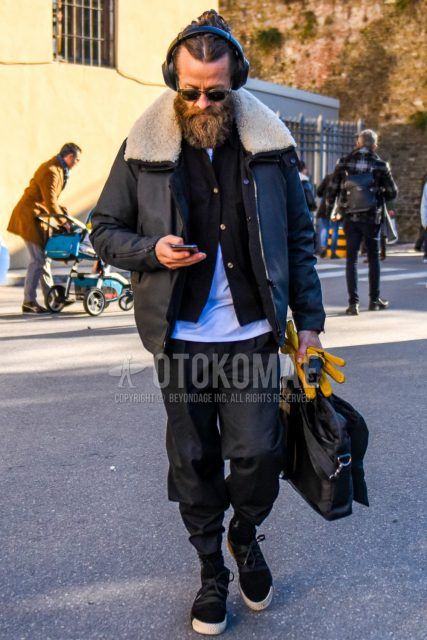 Men's coordinate and outfit with clear solid color sunglasses, solid color black leather jacket (not riders), solid color black cardigan, solid color white t-shirt, dark gray solid color slacks, black low-cut sneakers, and solid color black briefcase/handbag.