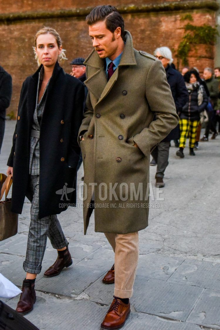 Men's coordinate and outfit with olive green solid color Ulster coat, blue solid color denim/chambray shirt, beige solid color winter pants (corduroy, velour), black solid color socks, brown wingtip leather shoes, red solid color tie.