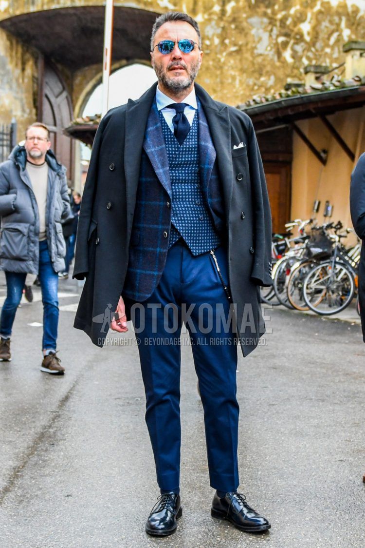 Men's outfit and outfit with plain sunglasses, plain black chester coat, plain white shirt, navy check tailored jacket, navy check gilet, plain blue slacks, plain navy socks, plain black plain toe leather shoes, and plain navy tie.