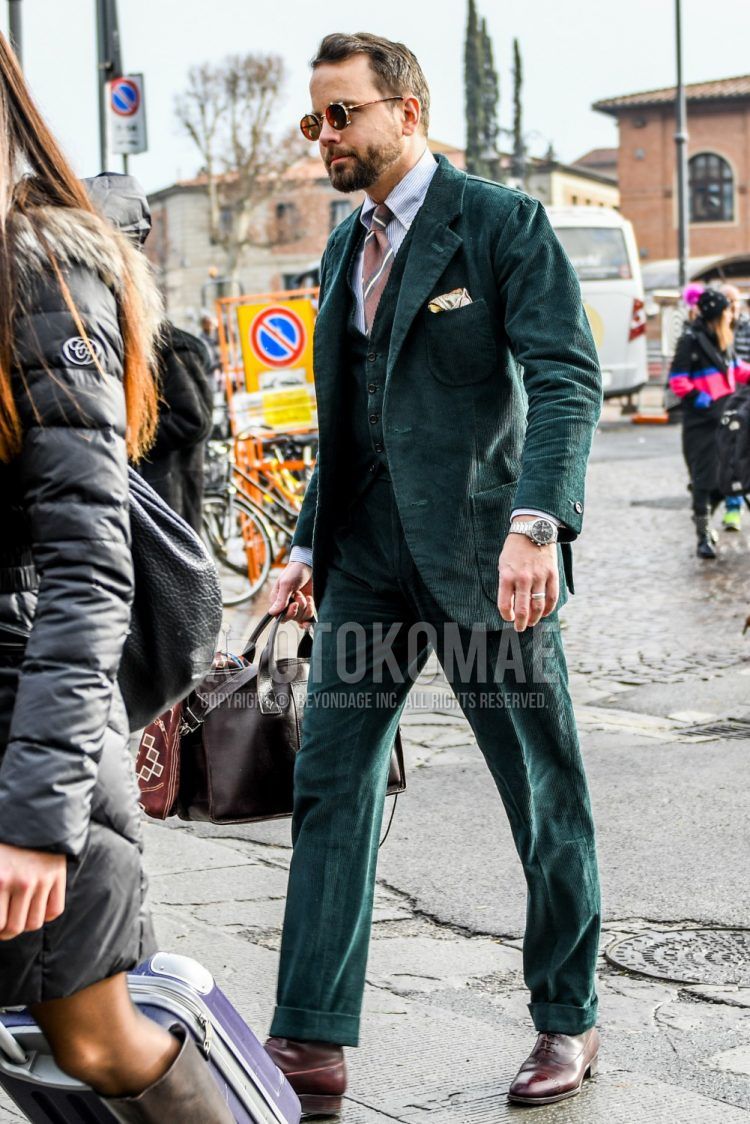 Men's coordinate and outfit with plain sunglasses, plain white shirt, brown plain toe leather shoes, plain green three-piece suit and red regimental tie.
