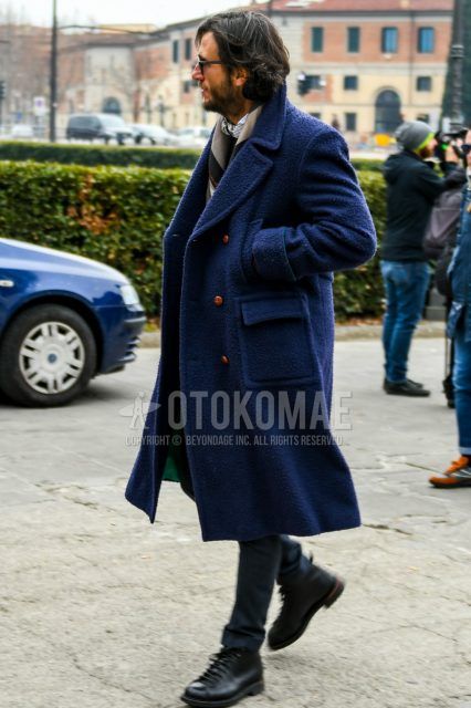 Men's coordinate and outfit with plain black sunglasses, beige scarf/stall, plain navy Ulster coat, plain navy slacks, and black work boots.