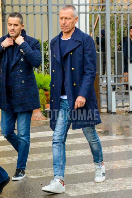 Winter men's coordinate and outfit with plain navy Ulster coat, plain navy sweater, plain white t-shirt, plain blue damaged jeans, and white low-cut sneakers.