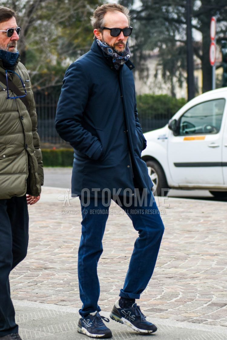 Men's coordinate and outfit with plain black Wellington sunglasses, brown scarf/stall, plain navy stainless steel coat, plain navy chinos, black socks socks, and premierta navy low-cut sneakers.