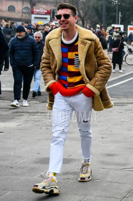 Men's coordinate and outfit with plain sunglasses, plain brown/white leather jacket (other than rider's), multi-colored top/inner sweater, plain white damaged jeans, white graphic socks, and multi-colored low-cut sneakers.