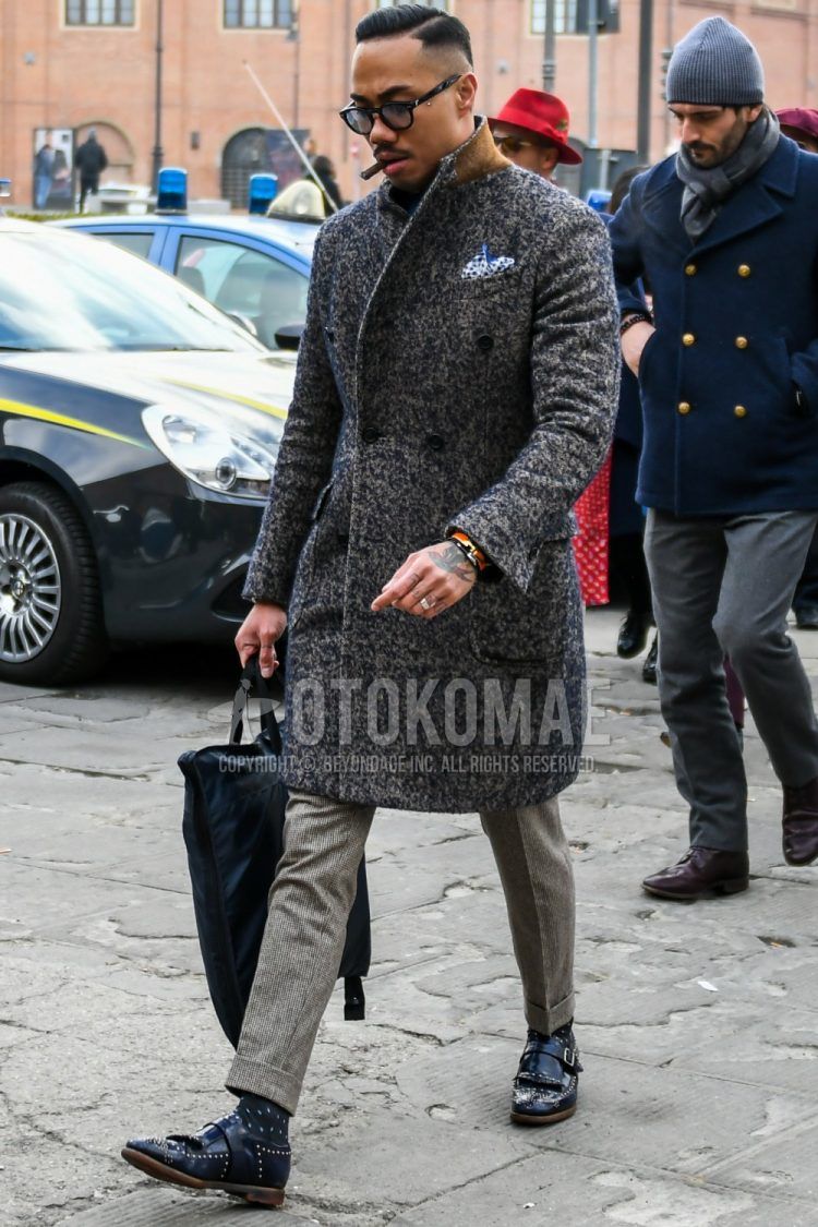 Men's coordinate and outfit with plain glasses, gray outer chester coat, gray bottom slacks, black dot socks, navy monk shoes leather shoes, and plain black briefcase/handbag.