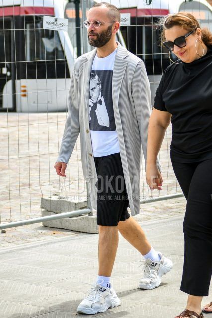 Men's coordinate and outfit with white striped chester coat, white striped outerwear, white graphic t-shirt, black striped shorts, plain white socks, and white low-cut sneakers.