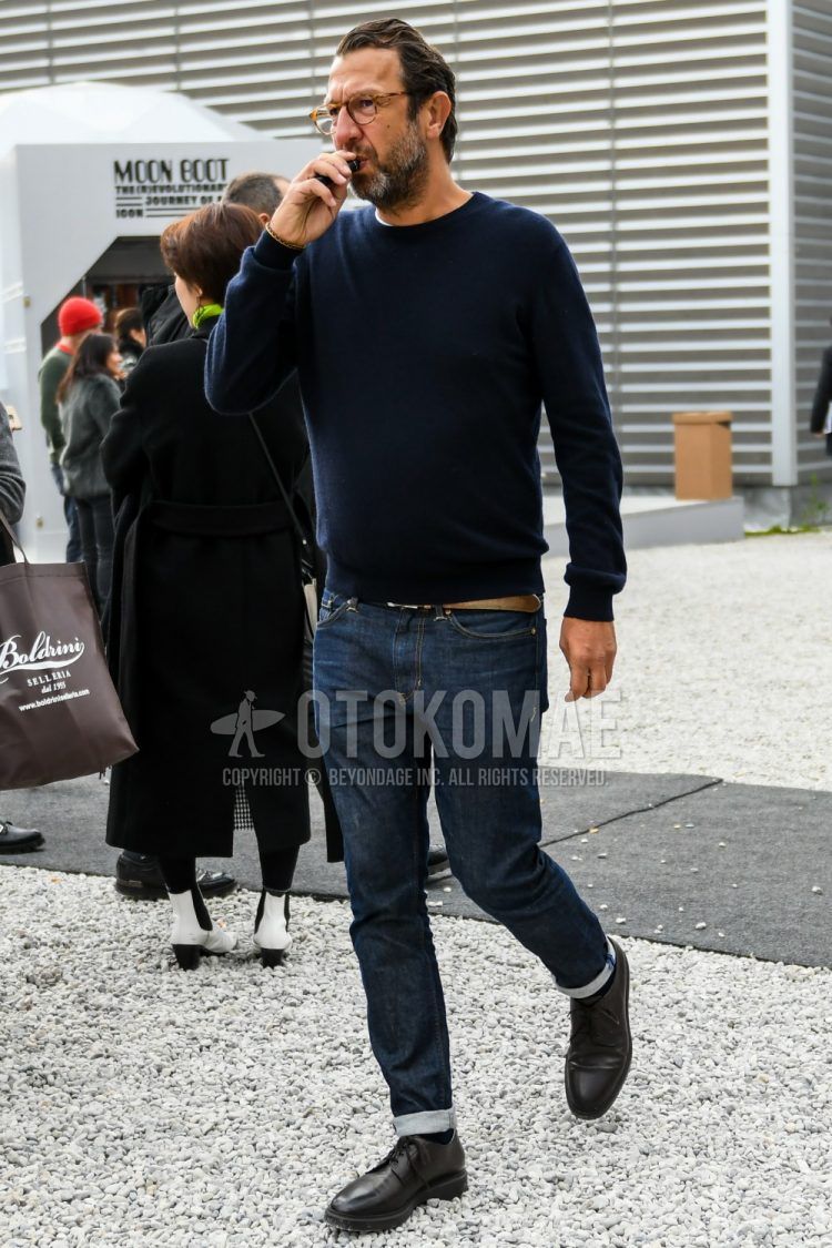 Men's coordinate and outfit with solid color glasses, solid color navy sweater, solid color brown leather belt, solid color navy denim/jeans and black plain toe leather shoes.
