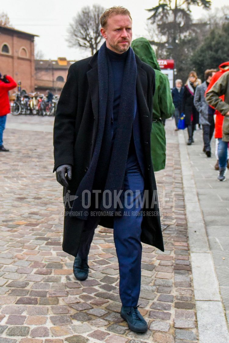 Men's coordinate and outfit with plain blue scarf/stall, plain black chester coat, plain navy turtleneck knit, plain blue slacks, and navy low-cut sneakers.