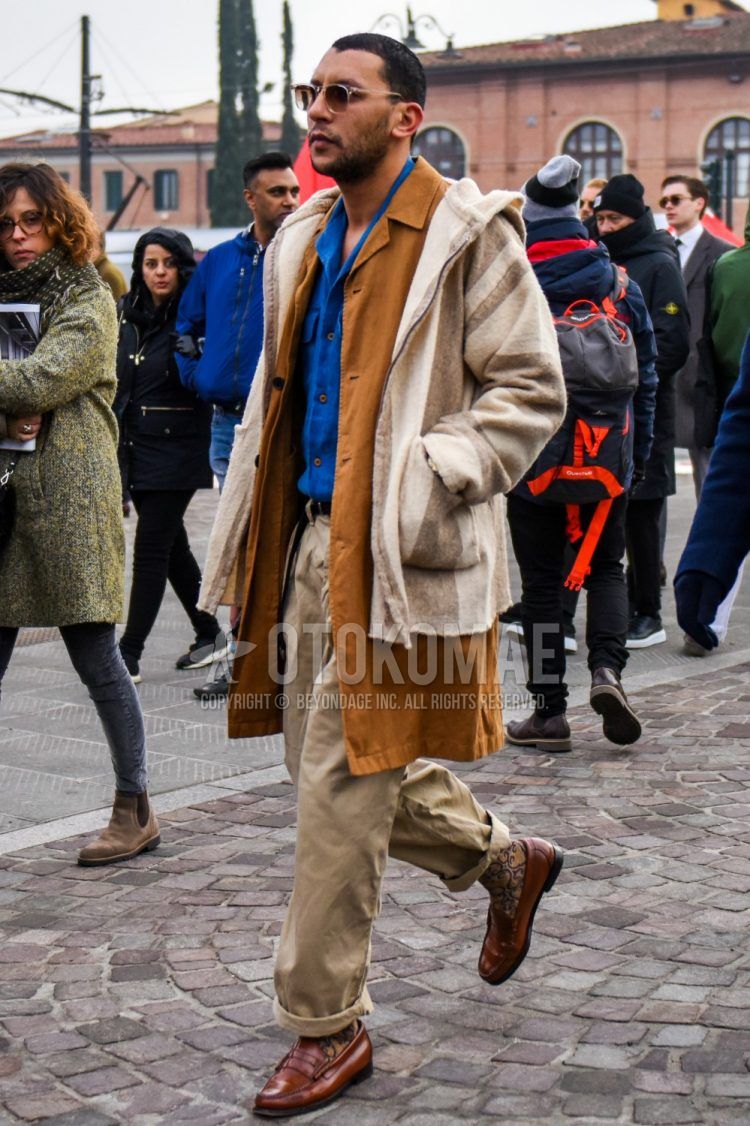 Men's coordinate and outfit with plain sunglasses, white/beige striped hooded coat, plain brown stainless steel collar coat, plain blue shirt, plain black leather belt, plain beige chinos and brown coin loafer leather shoes.