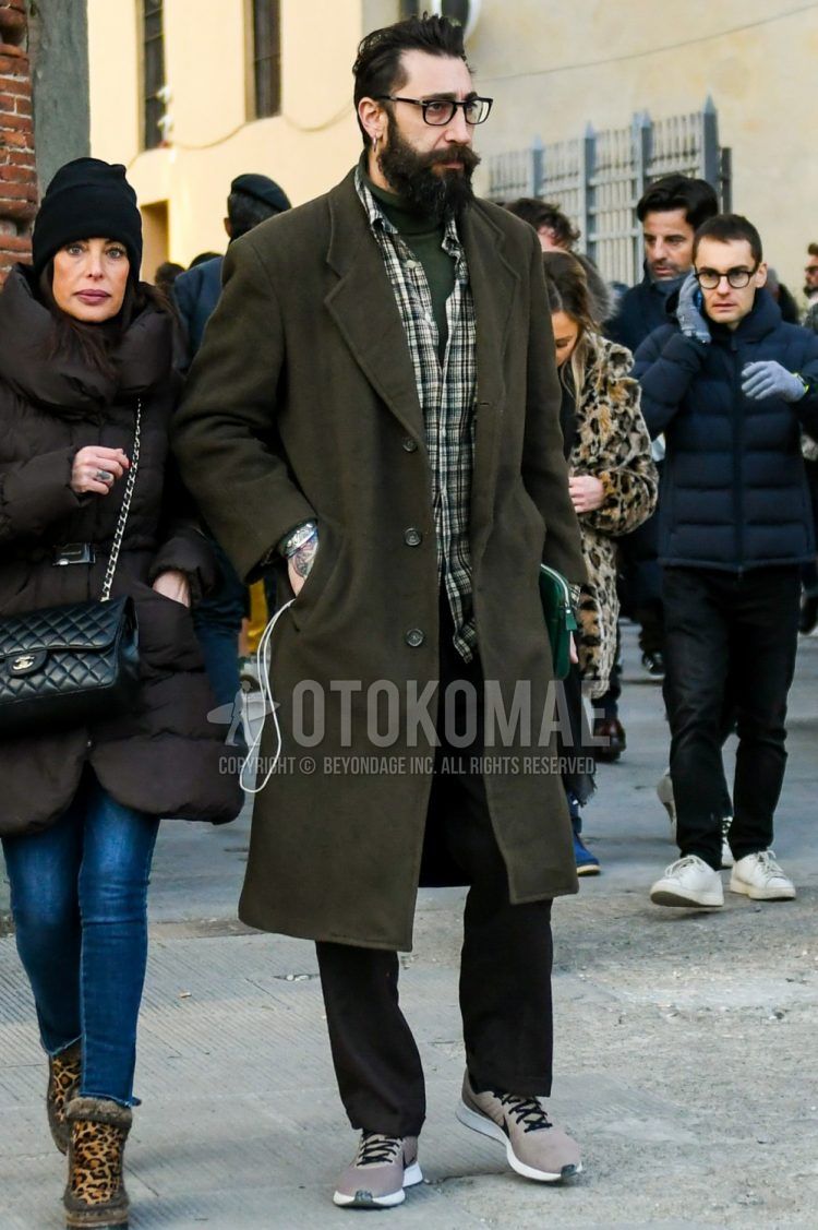Men's coordinate and outfit with plain black glasses, plain olive green chester coat, plain green turtleneck knit, black and white checked shirt, plain dark gray slacks, and Nike gray low-cut sneakers.