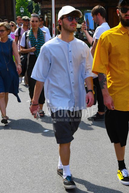 Men's spring/summer coordinate and outfit with plain white baseball cap, plain black sunglasses, band collar white striped shirt, plain gray shorts, plain white socks, and brown low-cut sneakers.