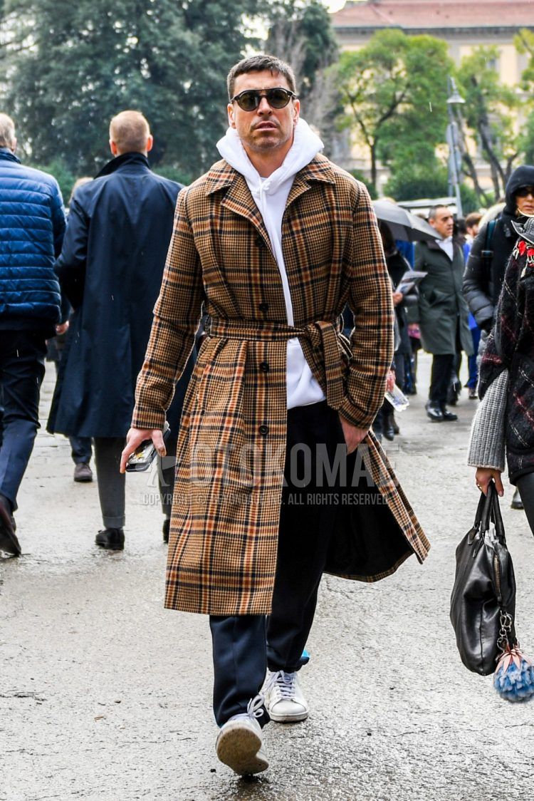 Men's coordinate and outfit with plain sunglasses, brown checked stainless steel coat, plain white hoodie, plain gray slacks, and white low-cut sneakers.