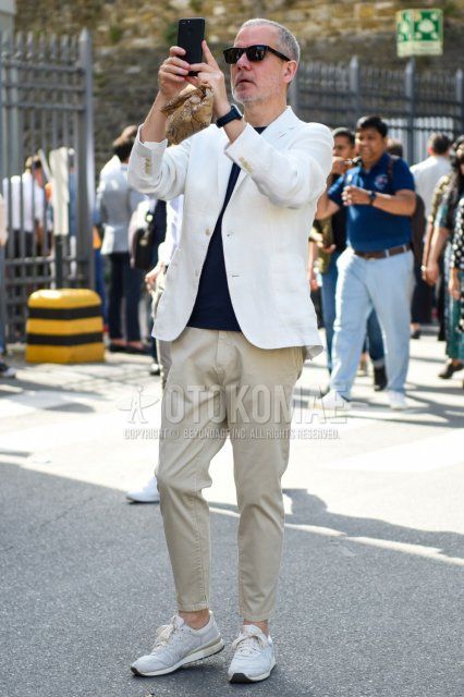 Men's coordinate and outfit with plain black sunglasses, plain white tailored jacket, plain navy t-shirt, plain beige chinos, plain beige ankle pants, and white low-cut sneakers from Onitsuka Tiger.