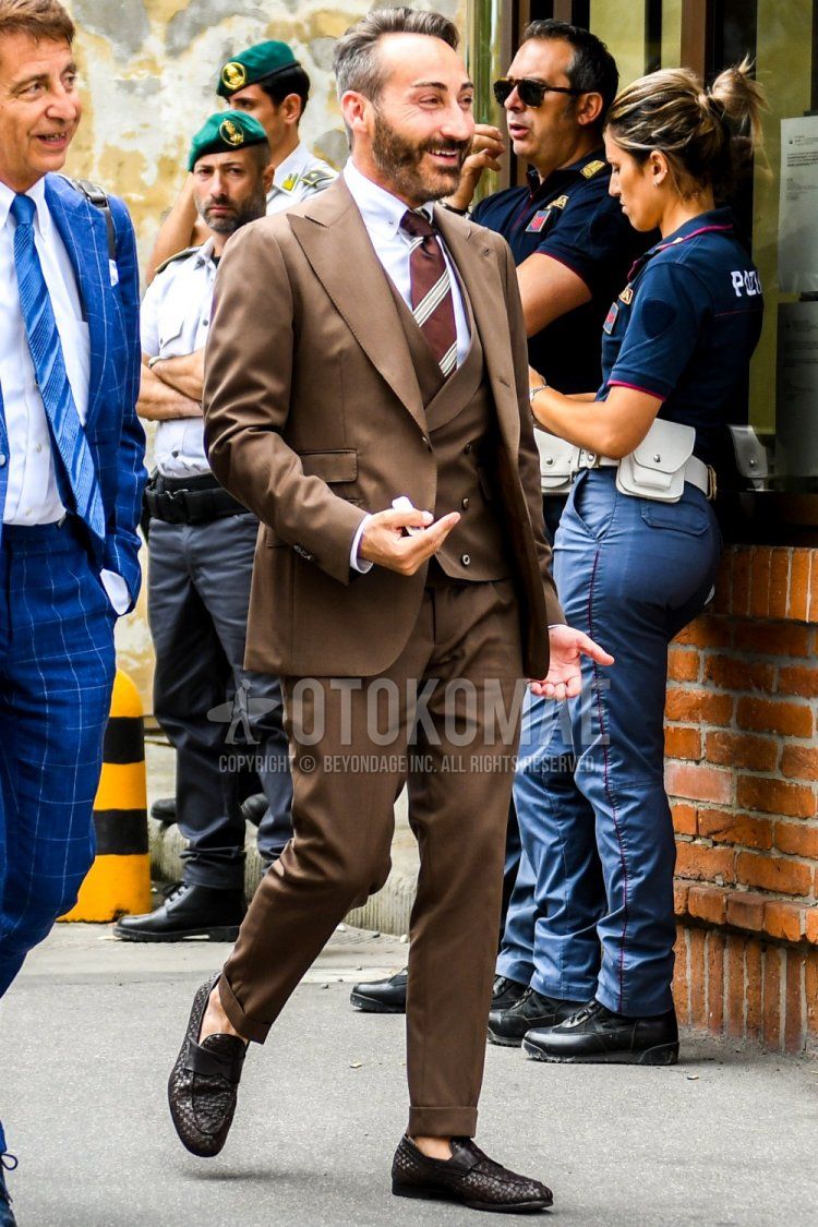 Men's coordinate and outfit with plain white shirt, brown coin loafer leather shoes, plain brown three-piece suit, and brown regimental tie.