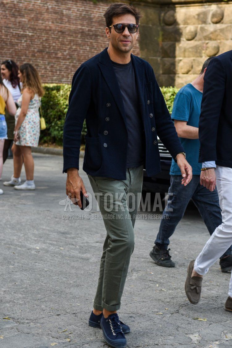 Men's coordination and outfit with Boston plain black sunglasses, plain navy tailored jacket, plain navy t-shirt, plain olive green cotton pants, and navy low-cut sneakers.