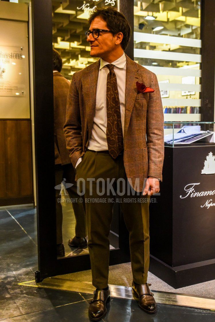 Men's coordination and outfit with plain glasses, brown checked tailored jacket, plain white shirt, olive green plain slacks, black monk shoes leather shoes and brown necktie.