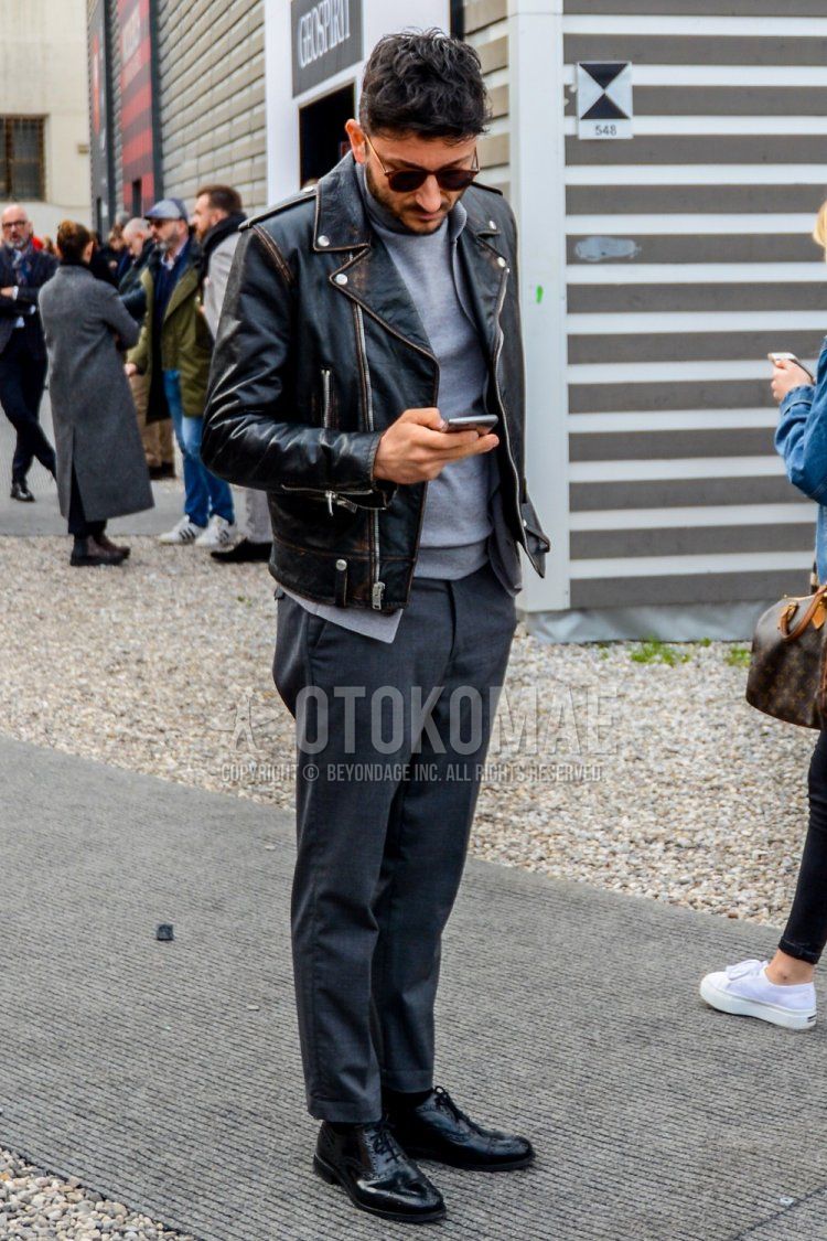 Men's coordinate and outfit with solid color sunglasses, solid color black rider's jacket, solid color gray turtleneck knit, solid color gray slacks and black straight tip leather shoes.