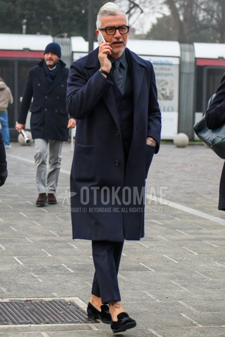 Winter men's outfit and outfit with Tom Ford plain black glasses, plain navy chester coat, plain black gilet, gray checked shirt, plain black ankle pants, dark gray plain slacks, black loafer leather shoes, and black checked tie.