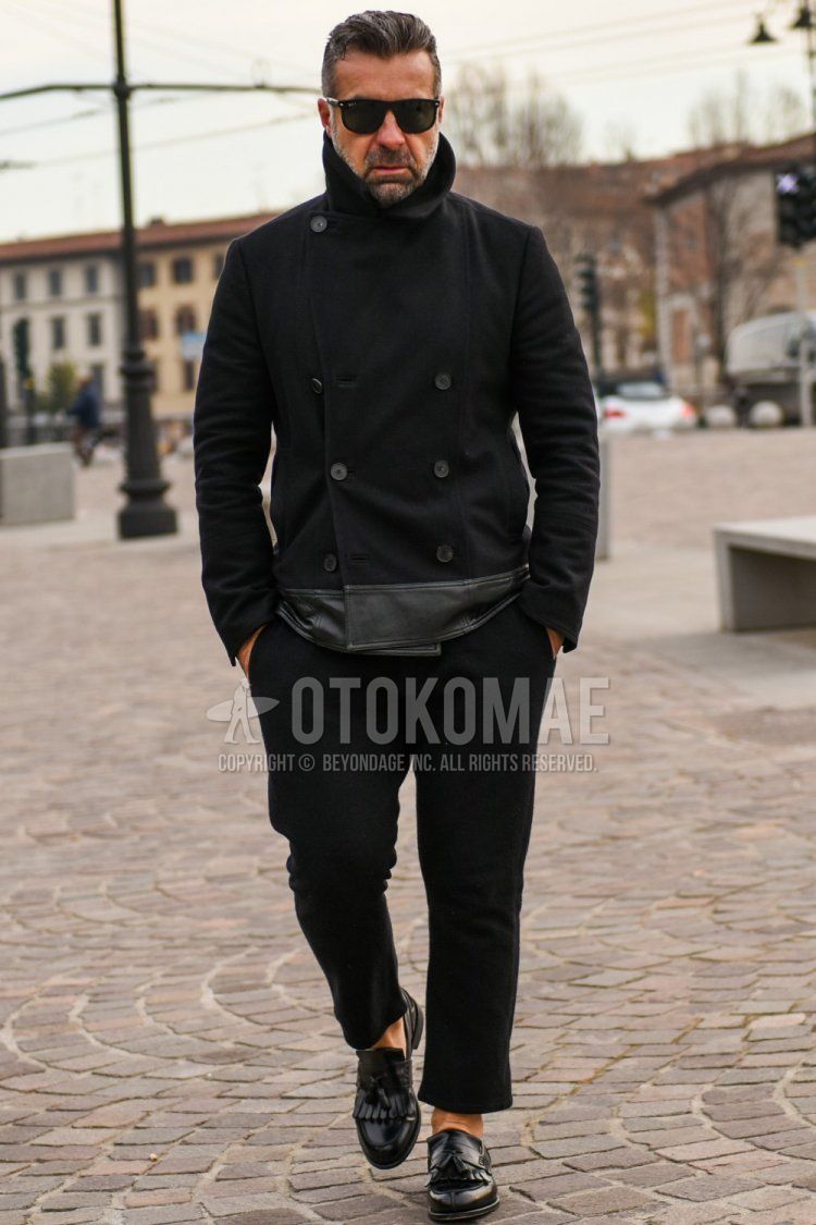 Men's fall/winter outfit with Ray-Ban Wellington plain black sunglasses, plain black P-coat, plain black ankle pants, plain black slacks, and black tassel loafer leather shoes.