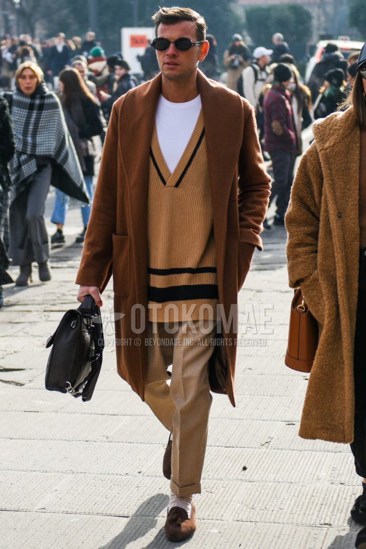 Men's outfit/clothing with solid color sunglasses, solid color brown outerwear, solid color brown sweater, solid color white t-shirt, solid color brown slacks, solid color white socks, brown tassel loafer leather shoes, and solid color black briefcase/handbag.