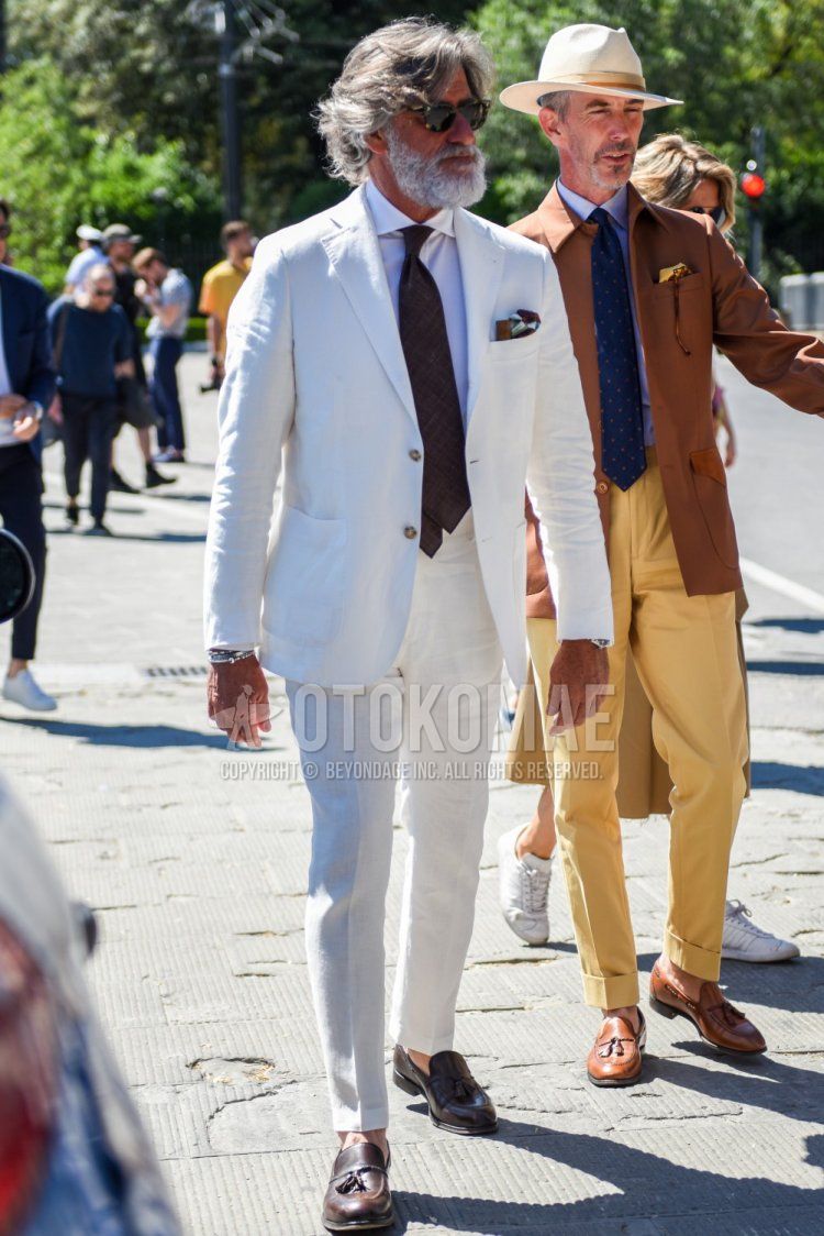 Men's coordinate and outfit with beige tortoiseshell sunglasses, plain white shirt, brown tassel loafer leather shoes, plain white suit, and brown necktie.