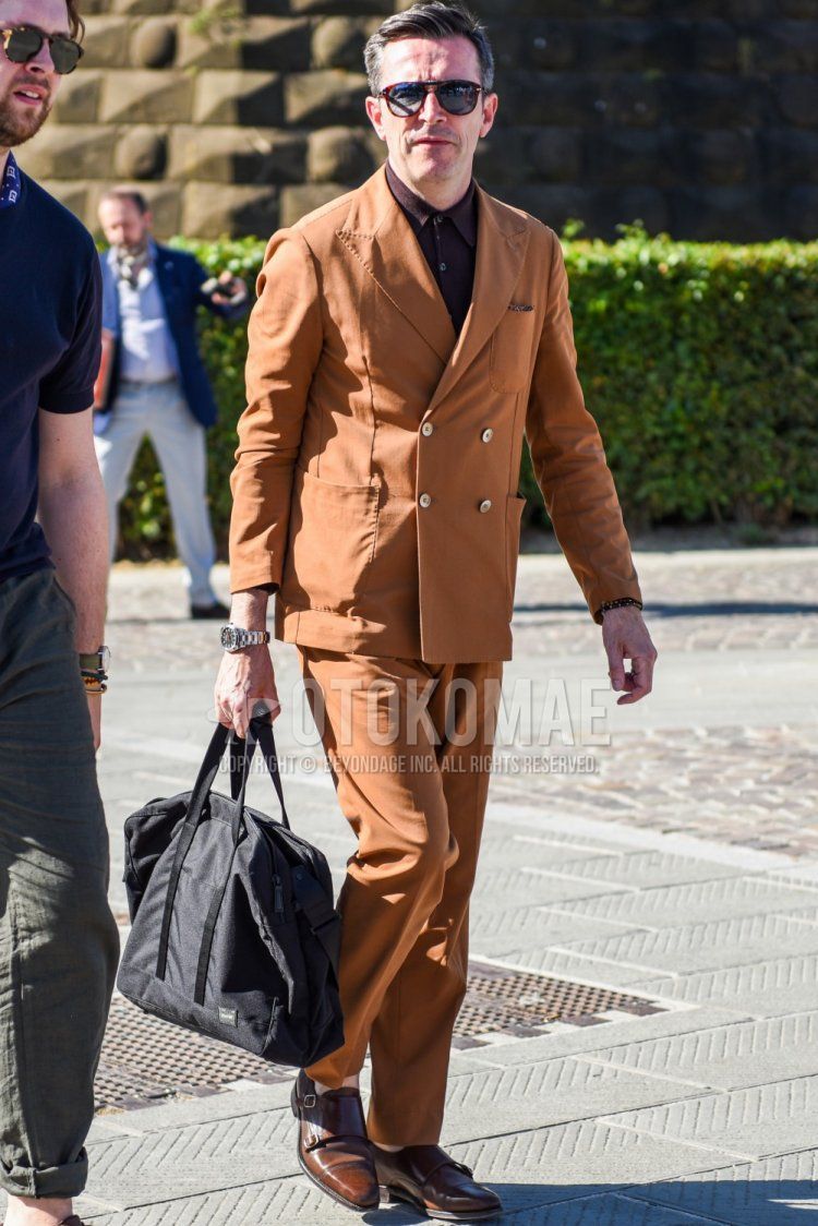 Men's coordination and outfit with plain brown/black sunglasses, plain brown shirt, brown monk shoes leather shoes, plain black Porter Boston bag, and plain brown suit.