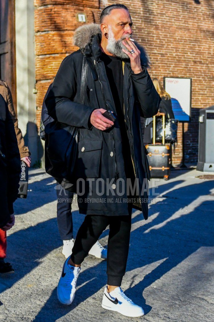 Men's coordinate and outfit with plain black down jacket, plain black shirt, plain black jogger pants/ribbed pants, and Nike white low-cut sneakers.