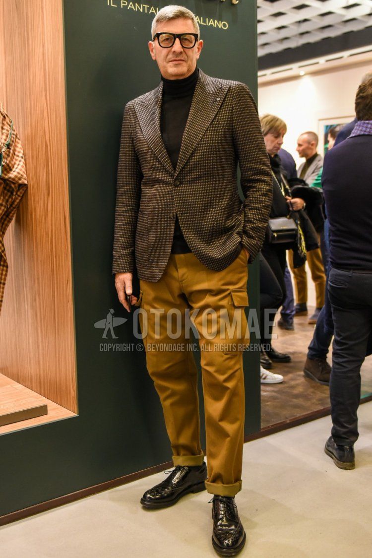 Men's spring and fall coordinate and outfit with plain black glasses, gray checked tailored jacket, plain black turtleneck knit, plain beige cargo pants, plain black socks, and brown wingtip leather shoes.