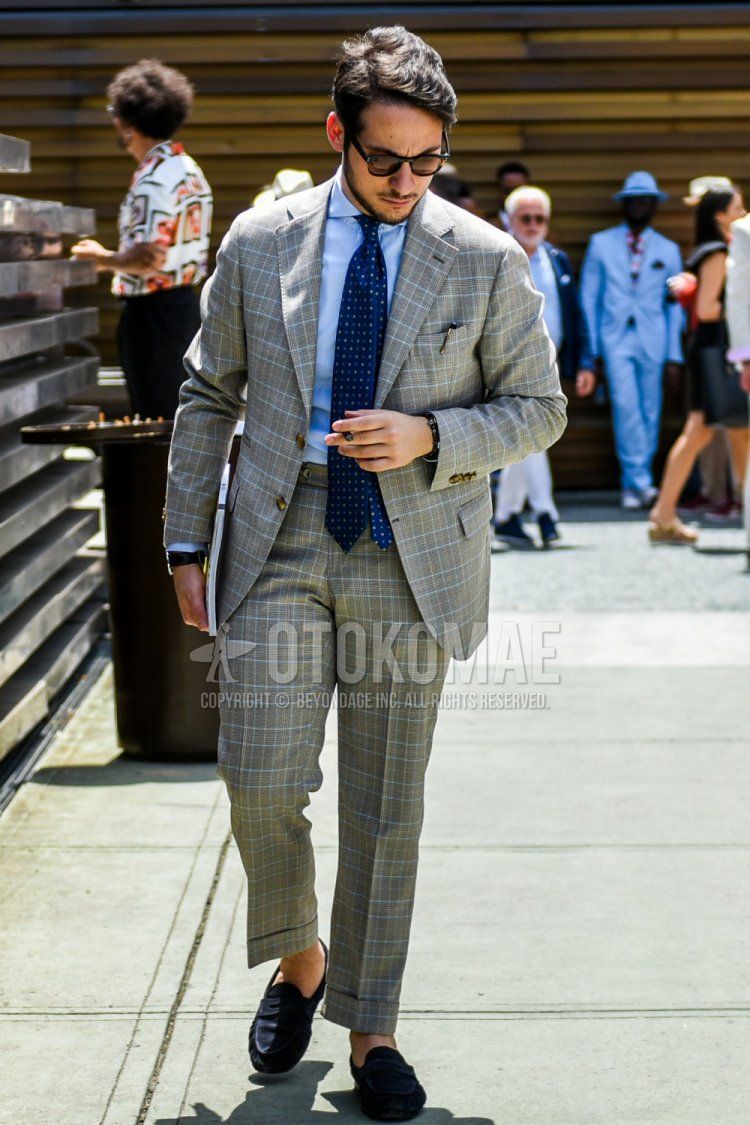 Men's coordinate and outfit with plain black sunglasses, plain light blue shirt, navy coin loafer leather shoes, gray checked suit, and navy dot tie.