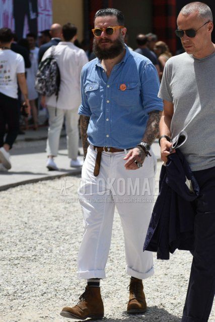 Men's coordinate and outfit with solid orange sunglasses, solid light blue denim/chambray shirt, solid brown leather belt, solid white wide-leg pants, solid multi-colored socks, and brown boots.
