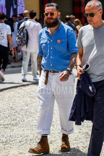 Men's coordinate and outfit with solid orange sunglasses, solid blue denim/chambray shirt, solid brown leather belt, solid white wide-leg pants, multi-colored striped socks, and brown work boots.