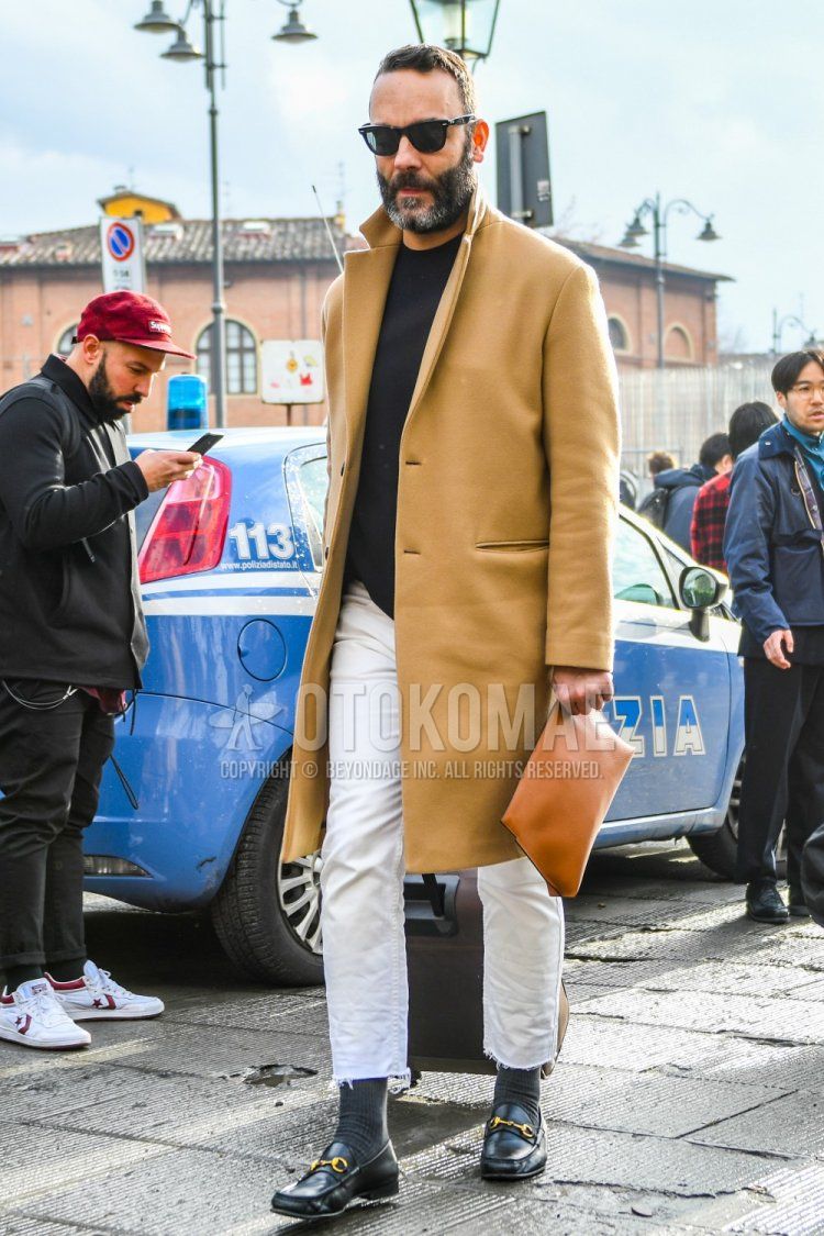 Men's outfit/combination of solid black sunglasses, solid beige chester coat, solid black sweater, solid white denim/jeans, solid gray socks, Gucci black bit loafer leather shoes, solid brown clutch/second bag/drawstring.