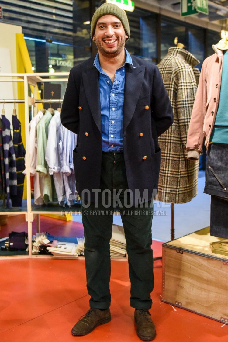 Men's fall outfit with olive green solid knit cap, navy solid tailored jacket, blue solid denim/chambray shirt, olive green solid chinos, black solid socks, suede brown plain toe leather shoes.