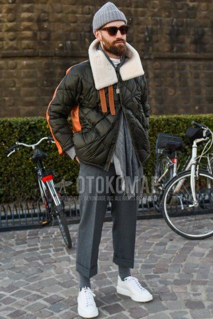 Men's fall/winter outfit with solid gray knit cap, brown tortoiseshell sunglasses, solid gray scarf/stall, solid olive green down jacket, solid gray slacks, solid gray cropped pants, solid gray socks, white low-cut sneakers Outfit.