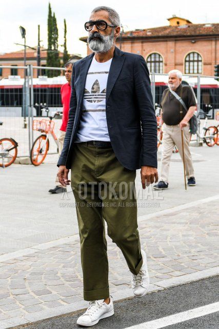 Men's coordinate and outfit with plain glasses, plain navy tailored jacket, Adidas t-shirt with white decal logo, plain black leather belt, olive green plain wide-leg pants, and white low-cut sneakers.