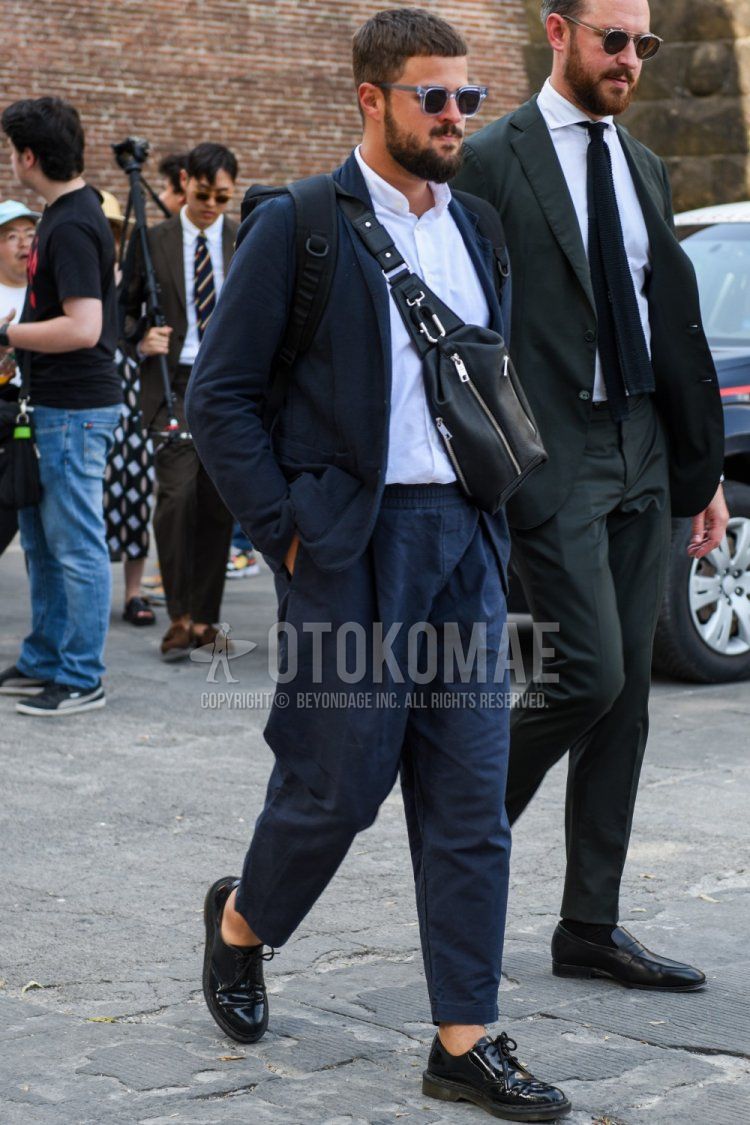 Men's coordinate and outfit with clear plain sunglasses, navy plain tailored jacket, white plain shirt, navy plain easy pants, plain ankle pants, black plain toe leather shoes, and black plain shoulder bag.