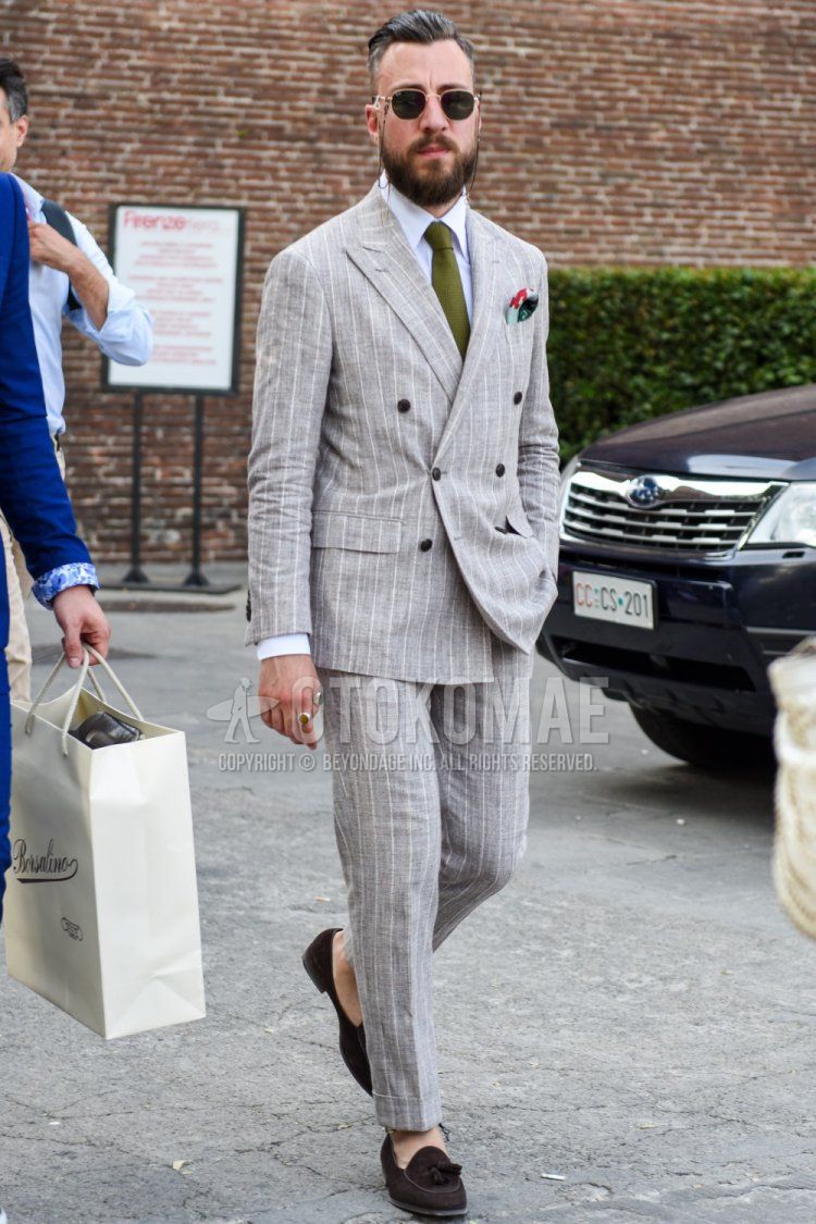 Men's coordinate and outfit with gold and black plain sunglasses, plain white shirt, brown tassel loafer leather shoes, gray striped suit, and olive green solid color tie.