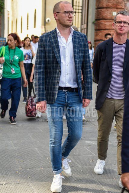 Men's spring, summer, and fall coordinate and outfit with plain black glasses, navy check tailored jacket, plain white shirt, plain navy mesh belt, plain blue denim/jeans, and white low-cut sneakers.