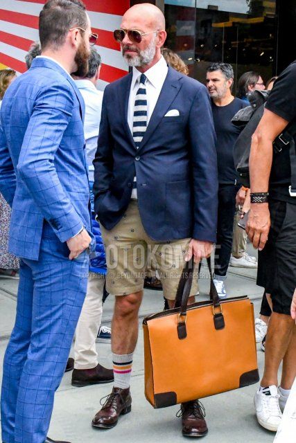 Men's coordinate with plain sunglasses, plain navy tailored jacket, plain white shirt, beige bottom shorts, white socks socks, brown plain toe leather shoes, plain brown briefcase/handbag, knit tie with navy and white stripes. How to wear.