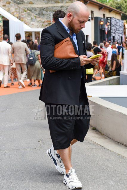 Men's coordinate and outfit with plain black tailored jacket, plain light blue shirt, plain black shorts, white low-cut sneakers, and plain brown clutch/second bag/drawstring bag.
