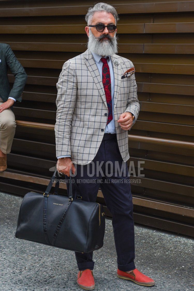 Men's spring and fall outfit with plain black sunglasses from Boston, grey checked tailored jacket, plain grey shirt, plain navy slacks, red slip-on sneakers, plain black Boston bag, and red tie tie.