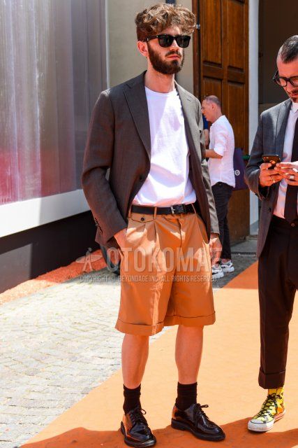 Men's coordinate and outfit with plain black sunglasses, plain gray tailored jacket, plain white T-shirt, plain black leather belt, plain beige/brown shorts, plain black socks, and black plain toe leather shoes.