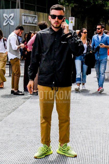 Men's coordinate and outfit with plain sunglasses, plain black coach jacket, plain beige chinos, and easy boost 350 semi-frozen yellow yellow low-cut sneakers.
