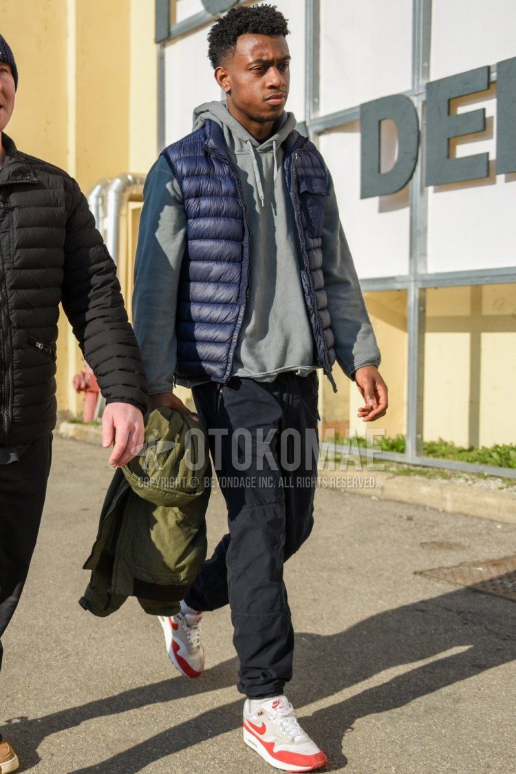 Men's fall/winter coordinate and outfit with solid navy inner down, solid gray hoodie, solid black jogger pants/ribbed pants, solid white socks, and Nike Air Max 1 gray/red low-cut sneakers.