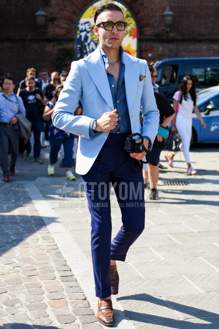 Men's coordinate and outfit with plain black glasses, plain light blue tailored jacket, plain blue shirt, plain navy slacks, and brown coin loafer leather shoes.