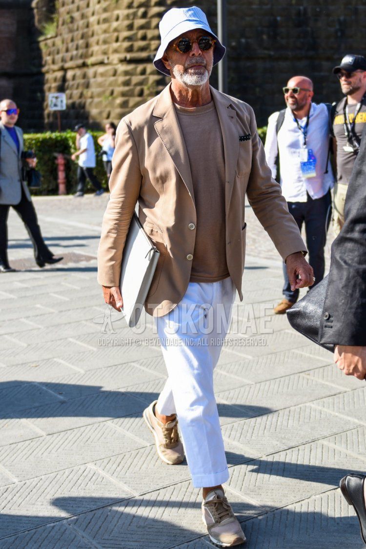 Men's coordinate and outfit with plain white hat, brown tortoiseshell sunglasses, plain tailored jacket, plain brown t-shirt, plain white cotton pants, and brown sneakers.