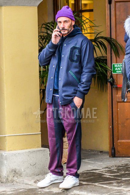 Men's coordinate and outfit with solid purple knit cap, solid purple stadium jacket, solid navy hoodie, solid purple easy pants, and white low-cut sneakers.