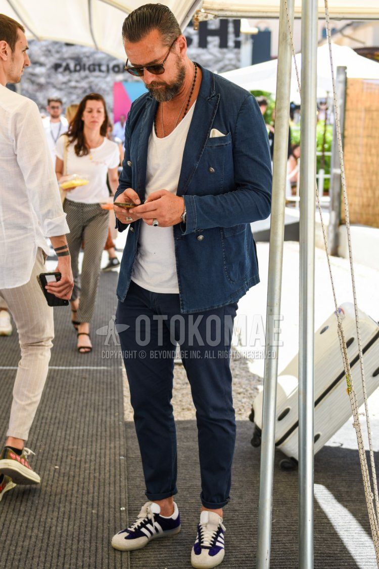 Men's coordinate and outfit with plain brown sunglasses, plain blue tailored jacket, plain white t-shirt, plain navy cotton pants, and Adidas purple and white low-cut sneakers.