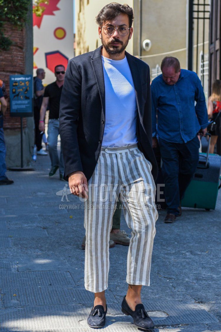 Men's coordinate and outfit with plain brown glasses, plain black tailored jacket, plain white T-shirt, white/beige striped cropped pants, and navy tassel loafer leather shoes.
